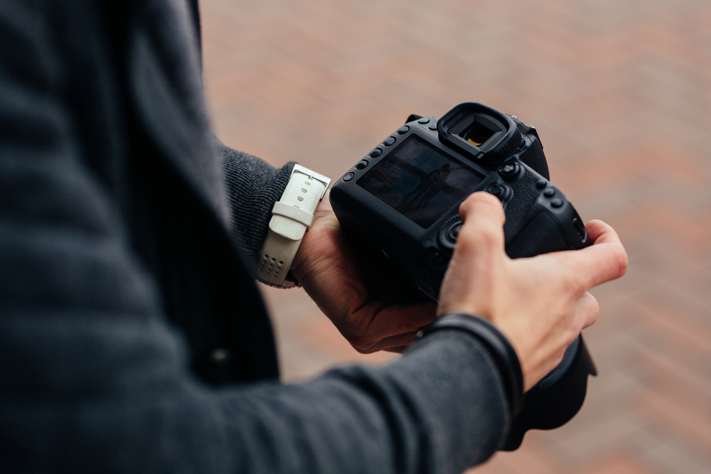 photographer holding professional camera looks photos outdoors